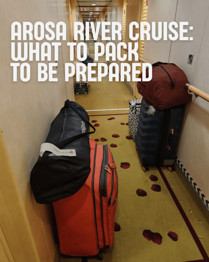 Text: Arosa river cruise: what to pack to be prepared. Picture: Orange suitcase with travel crib on top and a black suit case piled in an Arosa river cruise ship hallway during the departure process.
