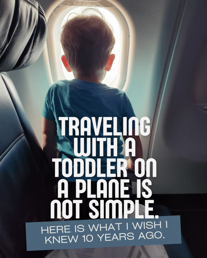 Toddler in blue shirt looking out airplane window seat during flight, traveling with a toddler on a plane, flying with a toddler title.