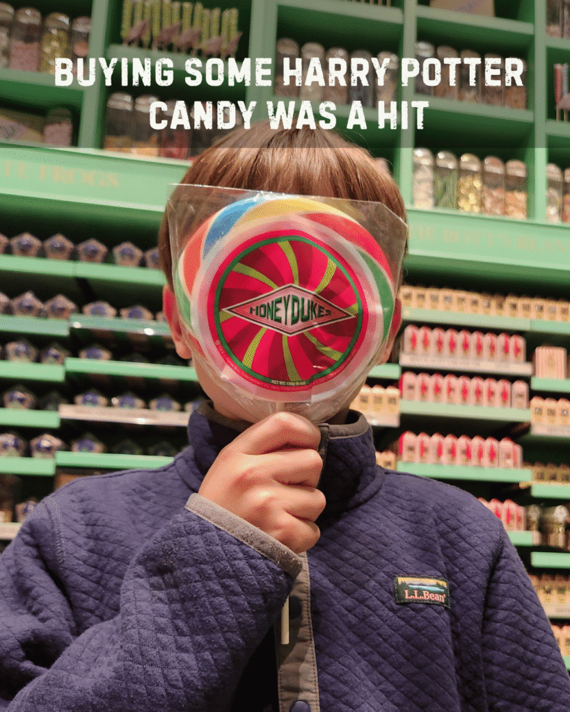 gift for 10 year old boys include candy. 10 year old boy is holding a Honey Dukes lolly pop in Harry Potter gift shop. The candy appears bigger than the boys head.