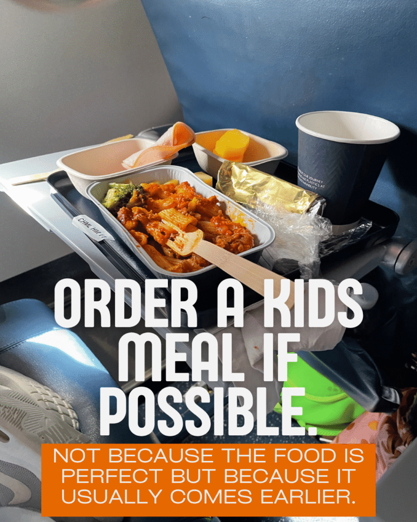 Kids airplane meal with pasta and fruit on tray table, ordering kids meal on flight for toddlers hack