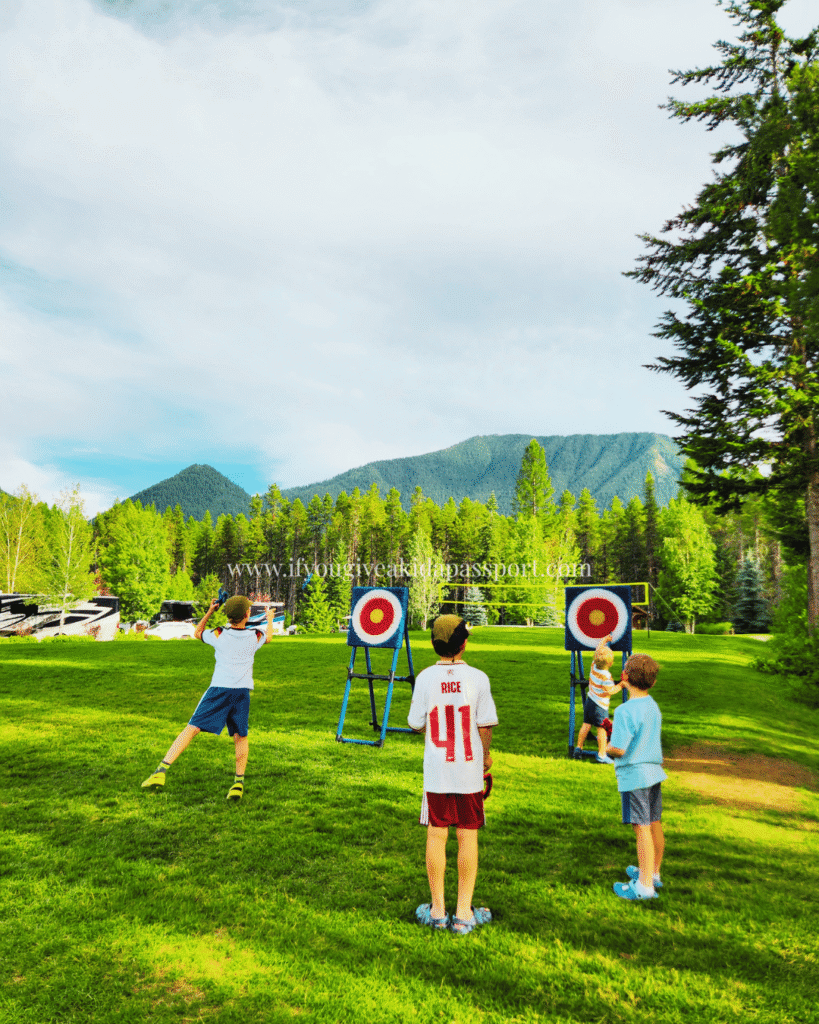 West Glacier KOA kids axe throwing game with Glacier NP mountains in the background.